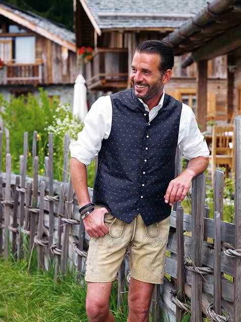 a model wearing MrLederhosen’s Bundhosen with a checked shirt and embroidered waistcoat. Highlight the texture of the leather and stitching.